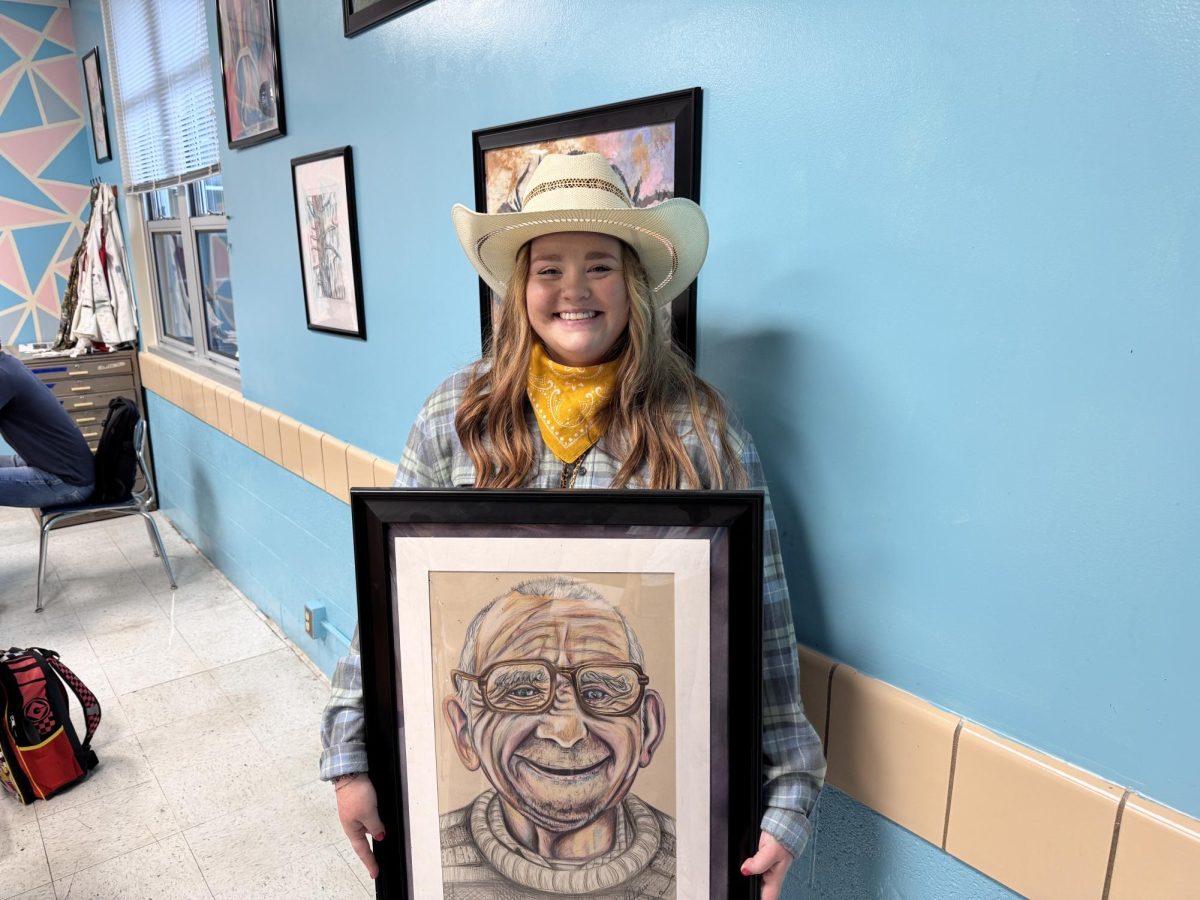 Art teacher Ms. Reichert holding a piece of her own artwork during Homecoming Spirit Week